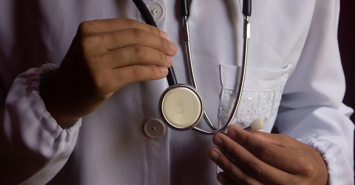 Une image en gros plan d'un médecin en blouse blanche tenant un stéthoscope, symbolisant la santé.