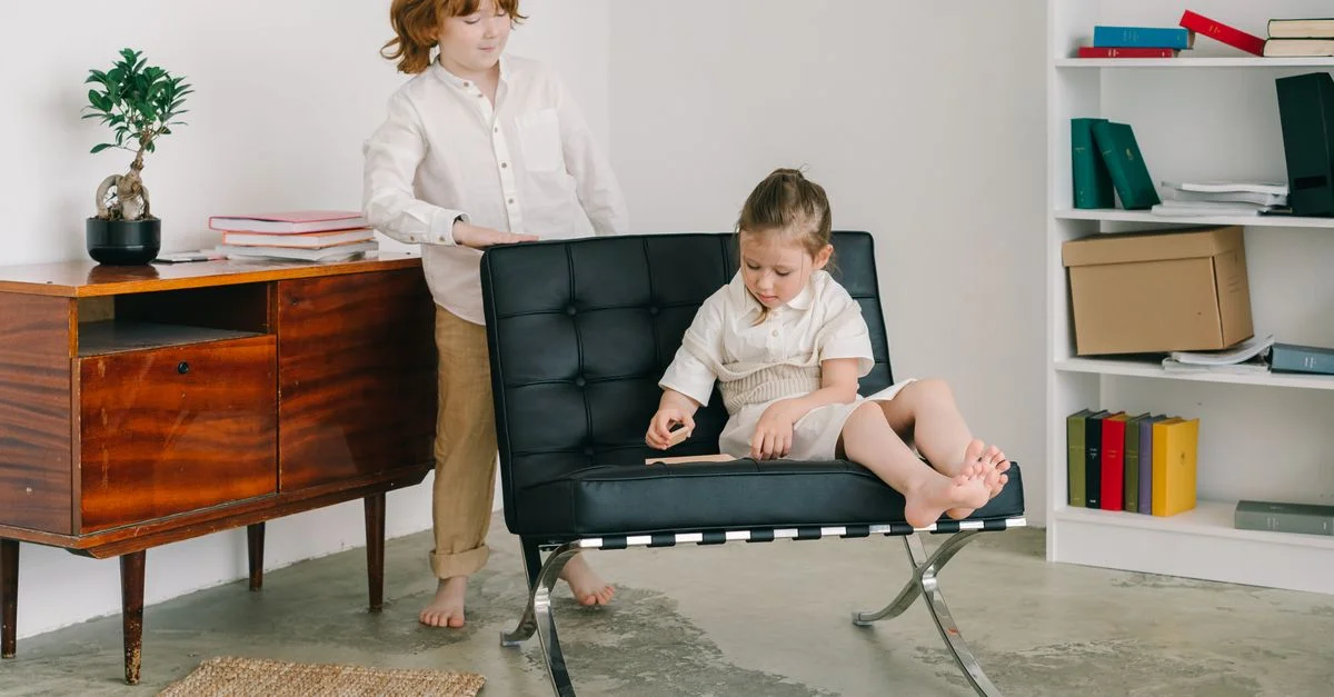 Deux enfants dans une pièce contemporaine, interagissant avec un livre et des meubles.