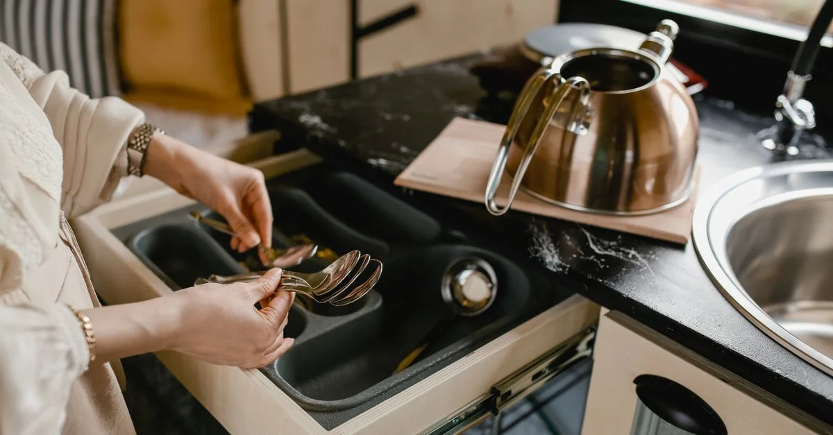 Une personne organise efficacement des couverts dans une cuisine minimaliste.