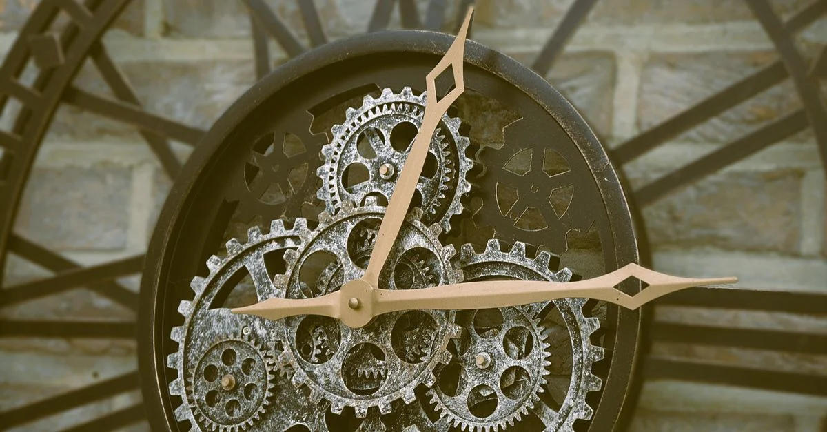 Gros plan sur une horloge murale rustique avec des rouages visibles, dégageant un charme ancien.