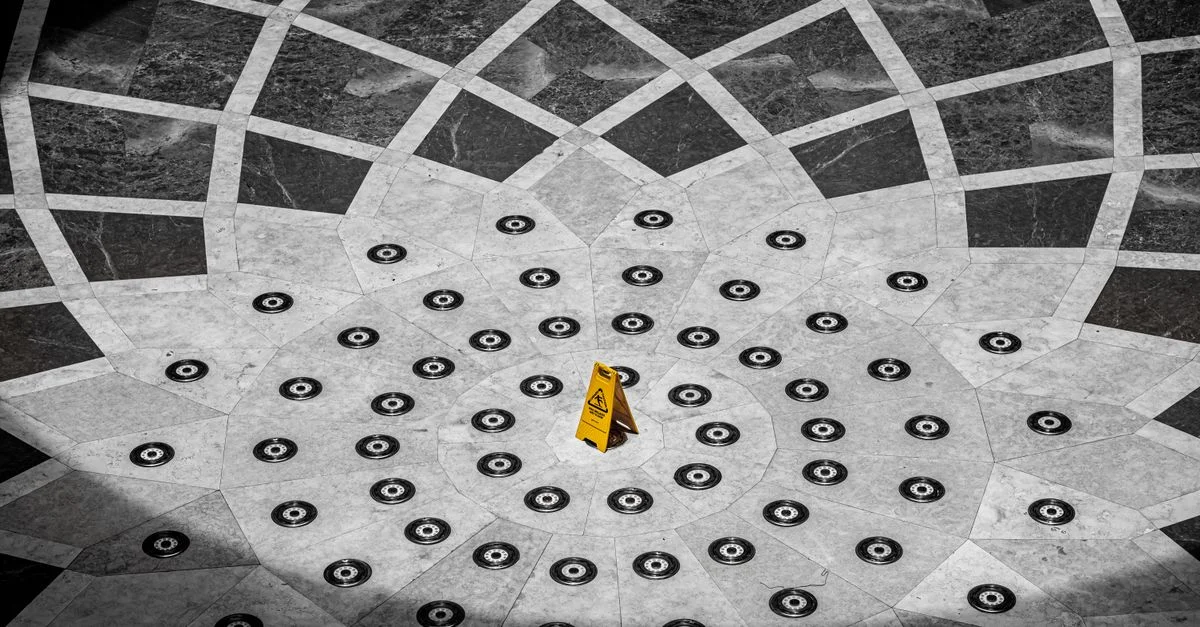 Motif de sol géométrique complexe avec un panneau de caution prominent à Cartagena, Colombie.