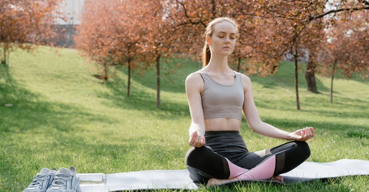 Une femme pratiquant la méditation sur un tapis de yoga dans un parc tranquille au printemps.