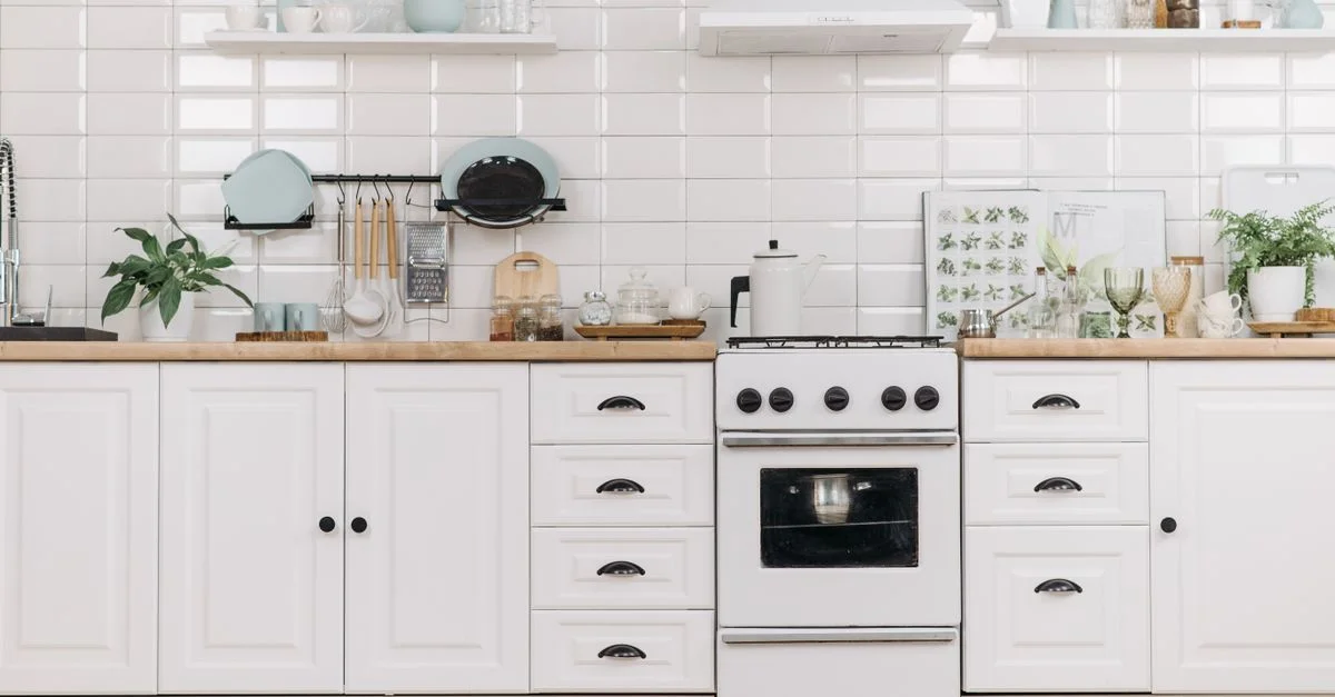 Cuisine minimaliste lumineuse avec des armoires blanches et une cuisinière, offrant un aspect propre et organisé.
